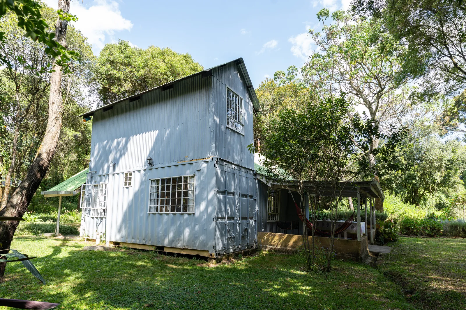 The tin-clad two-storey cottage at Gilgil Nest seen from the lawn, with the veranda to one side
