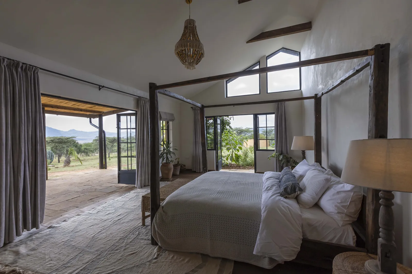 King room two at Lolldaiga Nest, a four poster bed under a beaded pendant light, with doors open onto the garden and plains