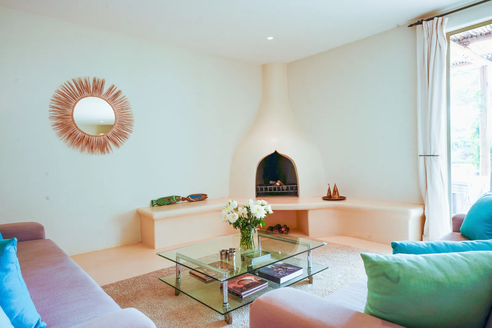 The living room at Nairobi Pool Nest, with a corner fireplace and a round mirror above it