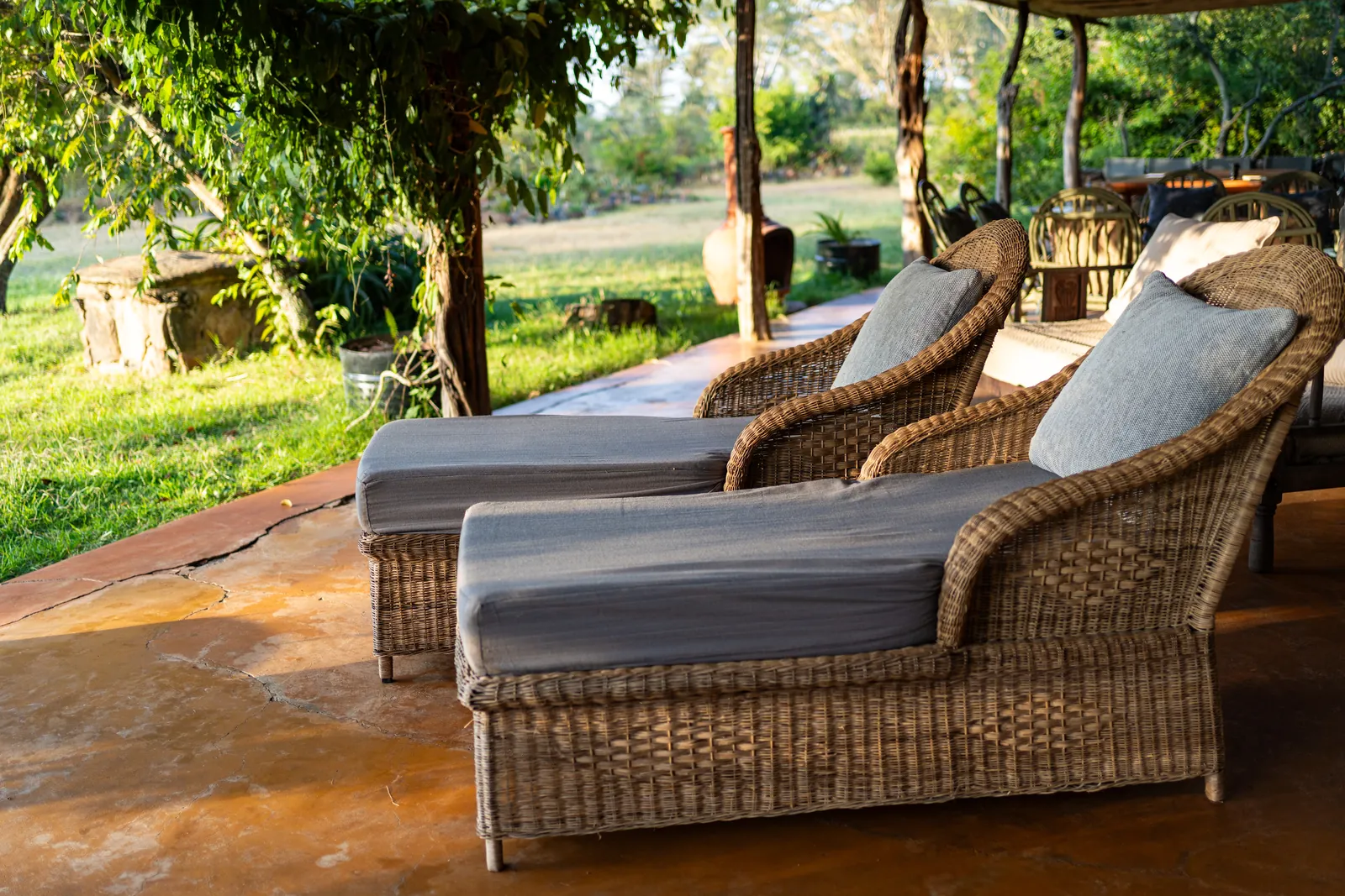 Two wicker loungers on the veranda at Laikipia Nest, looking out to the garden
