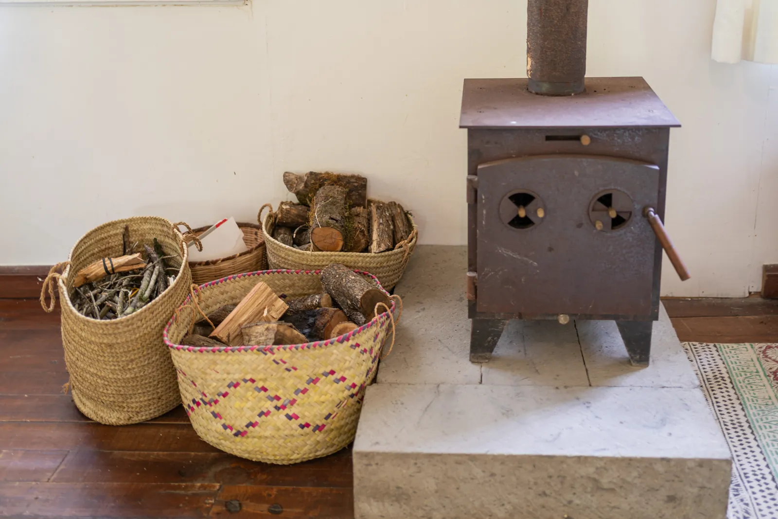 The wood burning stove at Gilgil Nest with woven baskets of logs beside it