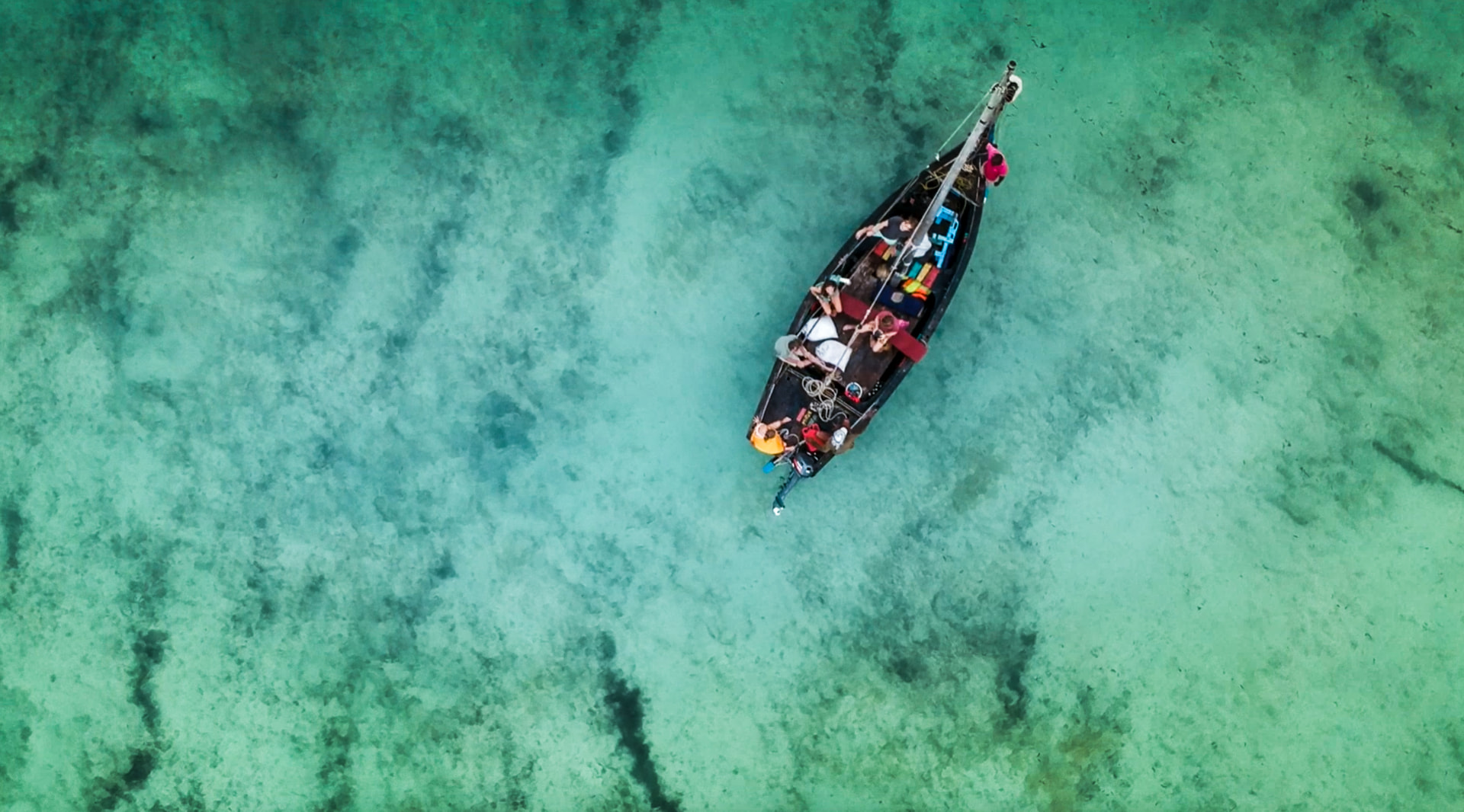 Aerial view of a traditional dhow anchored on clear turquoise water over the reef off the Kenyan coast