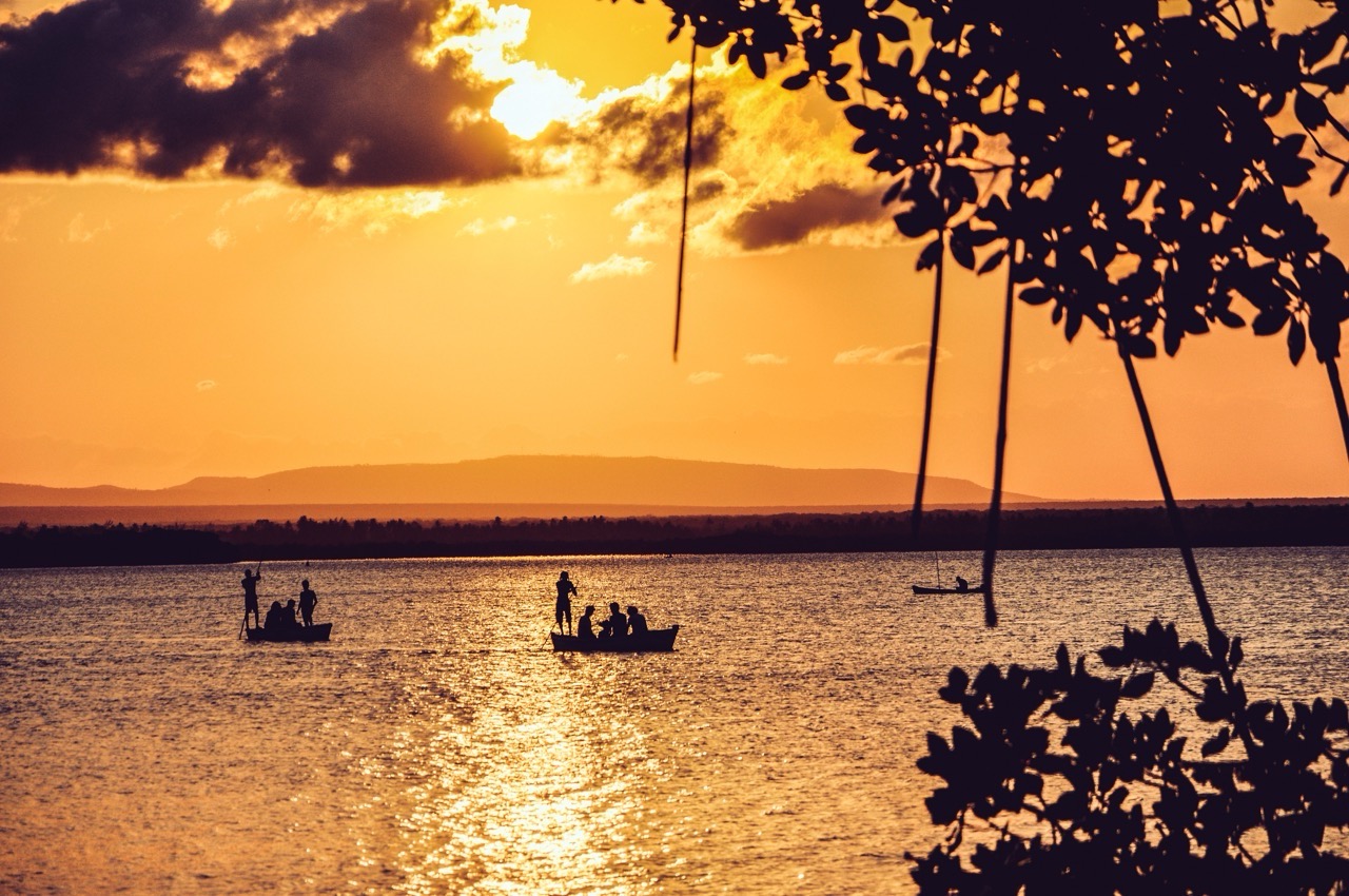 Two people paddling a wooden canoe on still water at sunset