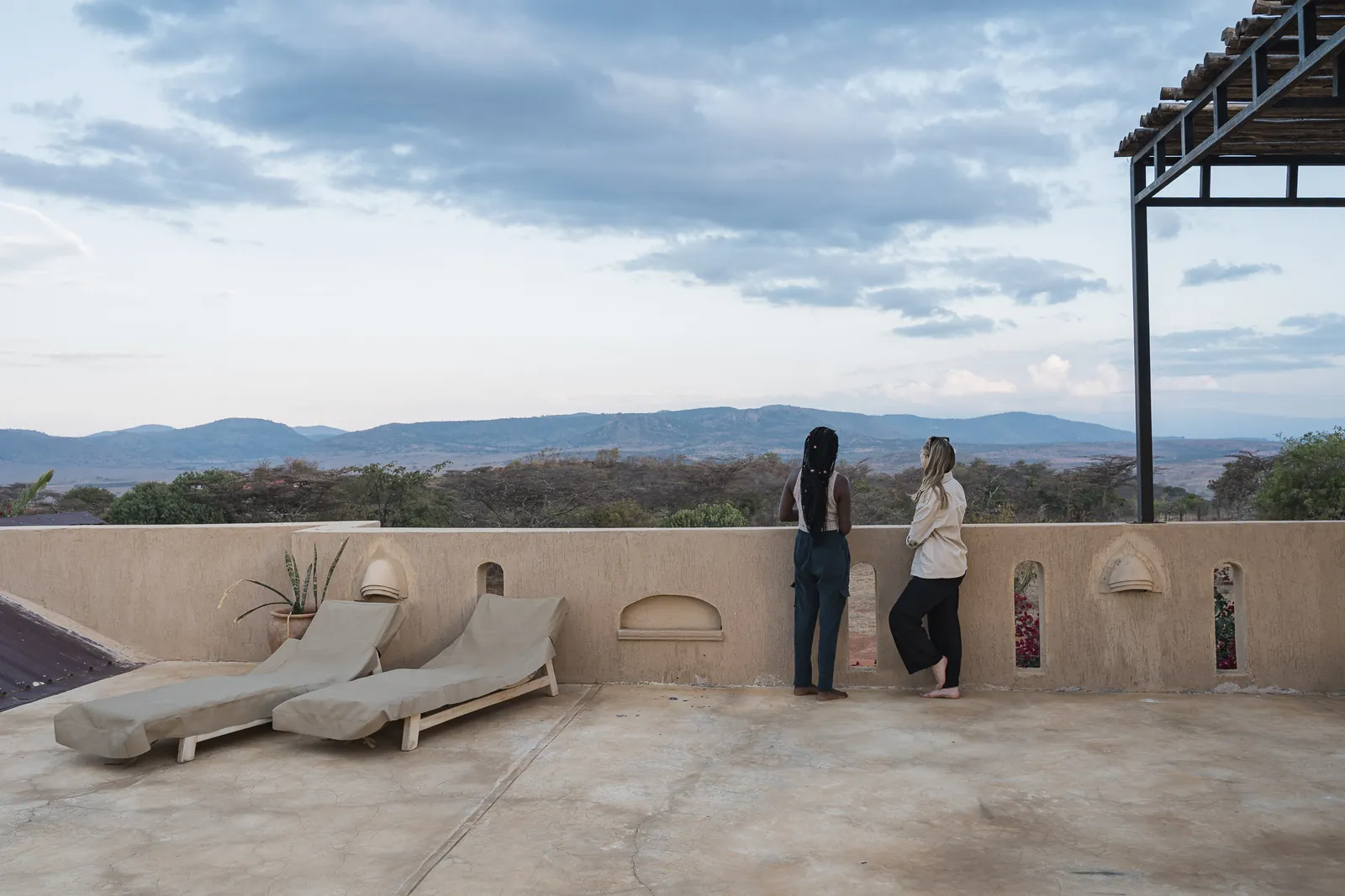 Two guests on the rooftop terrace at Lolldaiga Nest, beside two loungers, looking over the valley