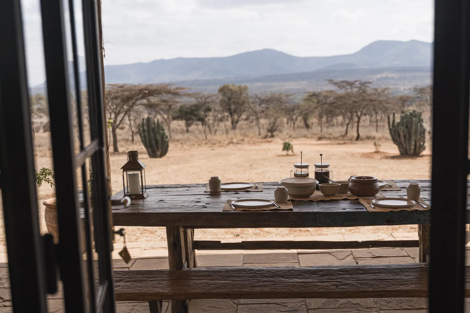 The verandah table at Lolldaiga Nest seen through open steel doors, with the hills beyond