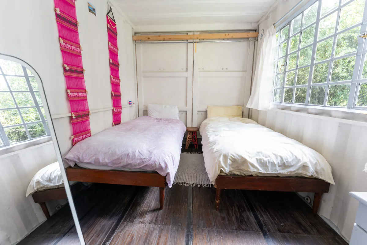 Bedroom two at Gilgil Nest, two single beds on a dark wood floor between two windows