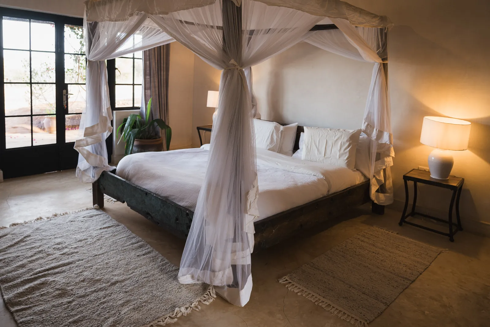 A bedroom at Lolldaiga Nest with a dark wood four poster bed draped in a white net