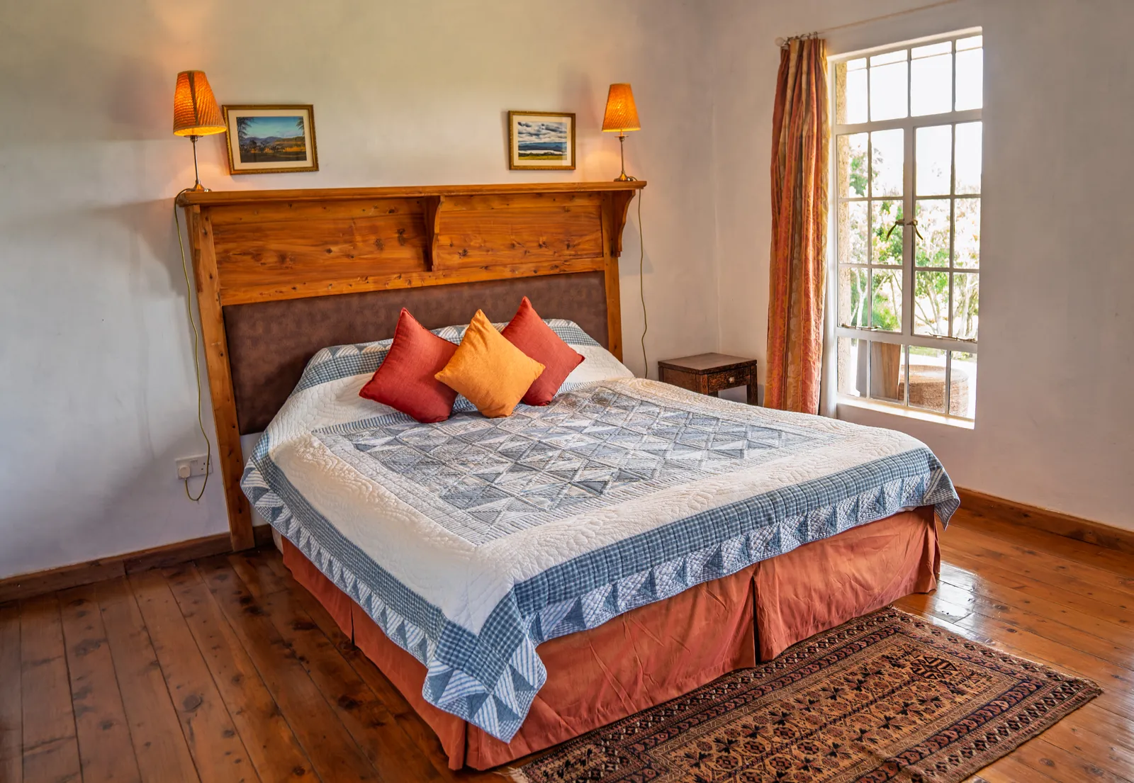 A bedroom at Asili Cottage with a patterned quilt and wooden floors