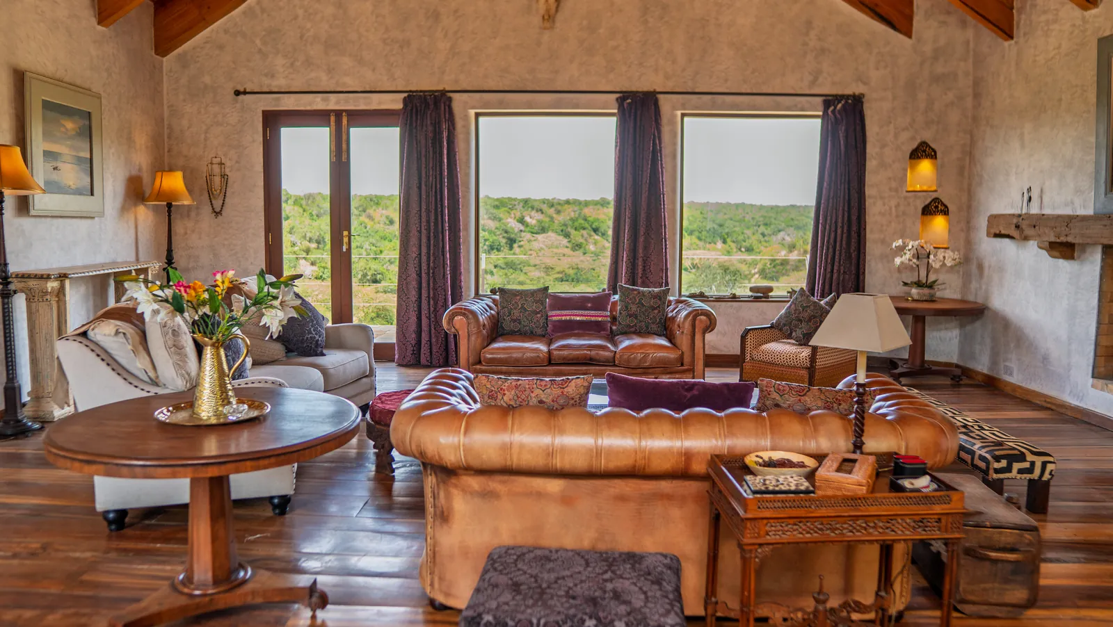 The great room at Asili House, with leather sofas and wide windows onto the bush