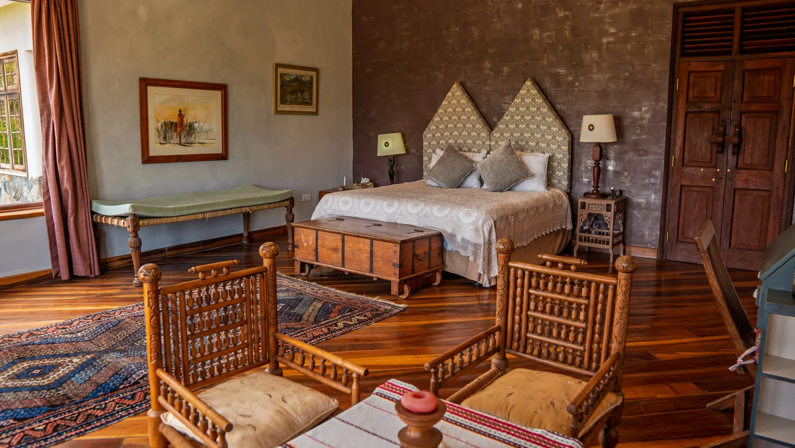 A bedroom at Asili House with carved wooden chairs at the foot of the bed