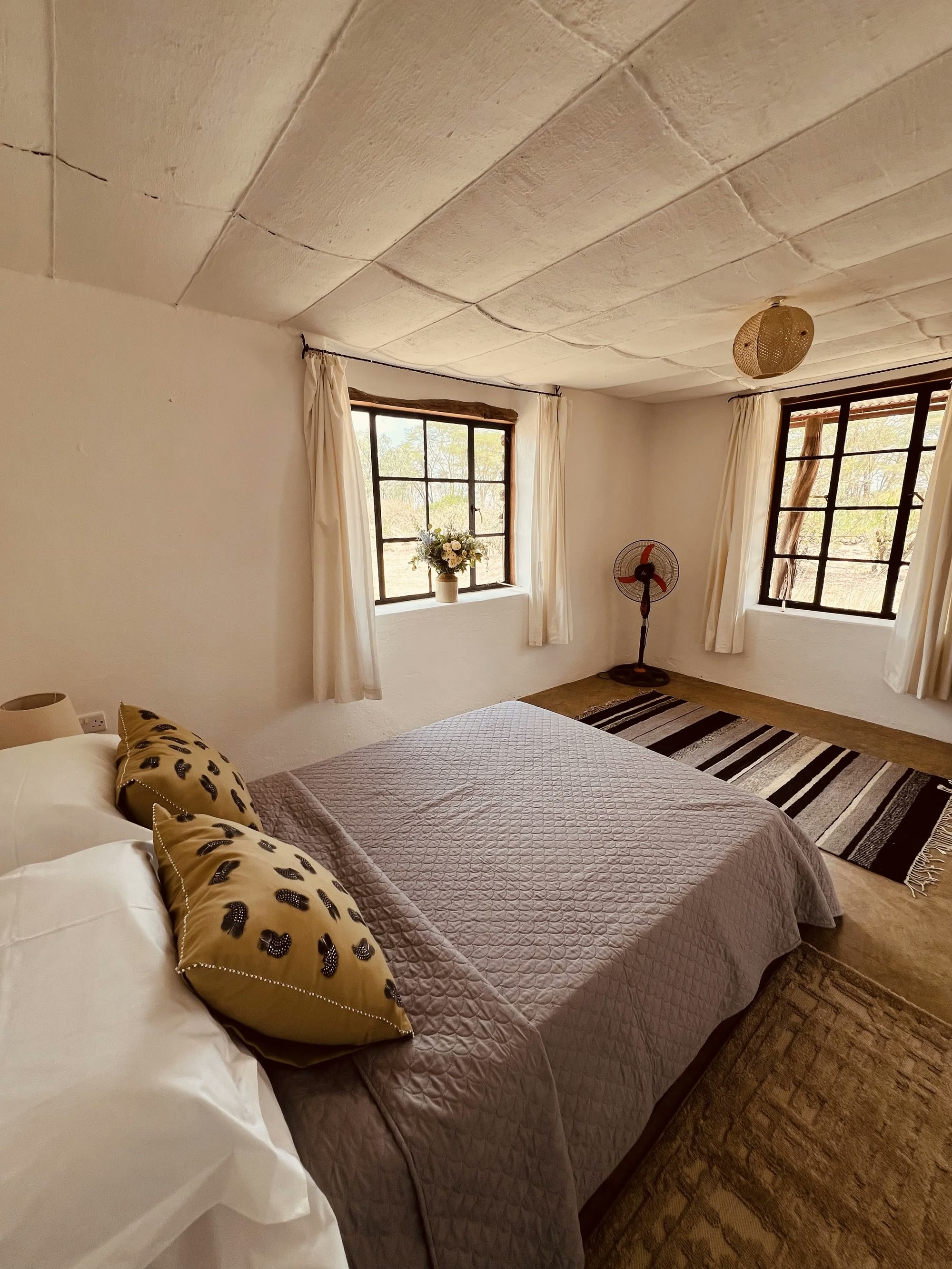 Double bedroom in the Laikipia Nest cottage with a quilted bedspread and striped rug