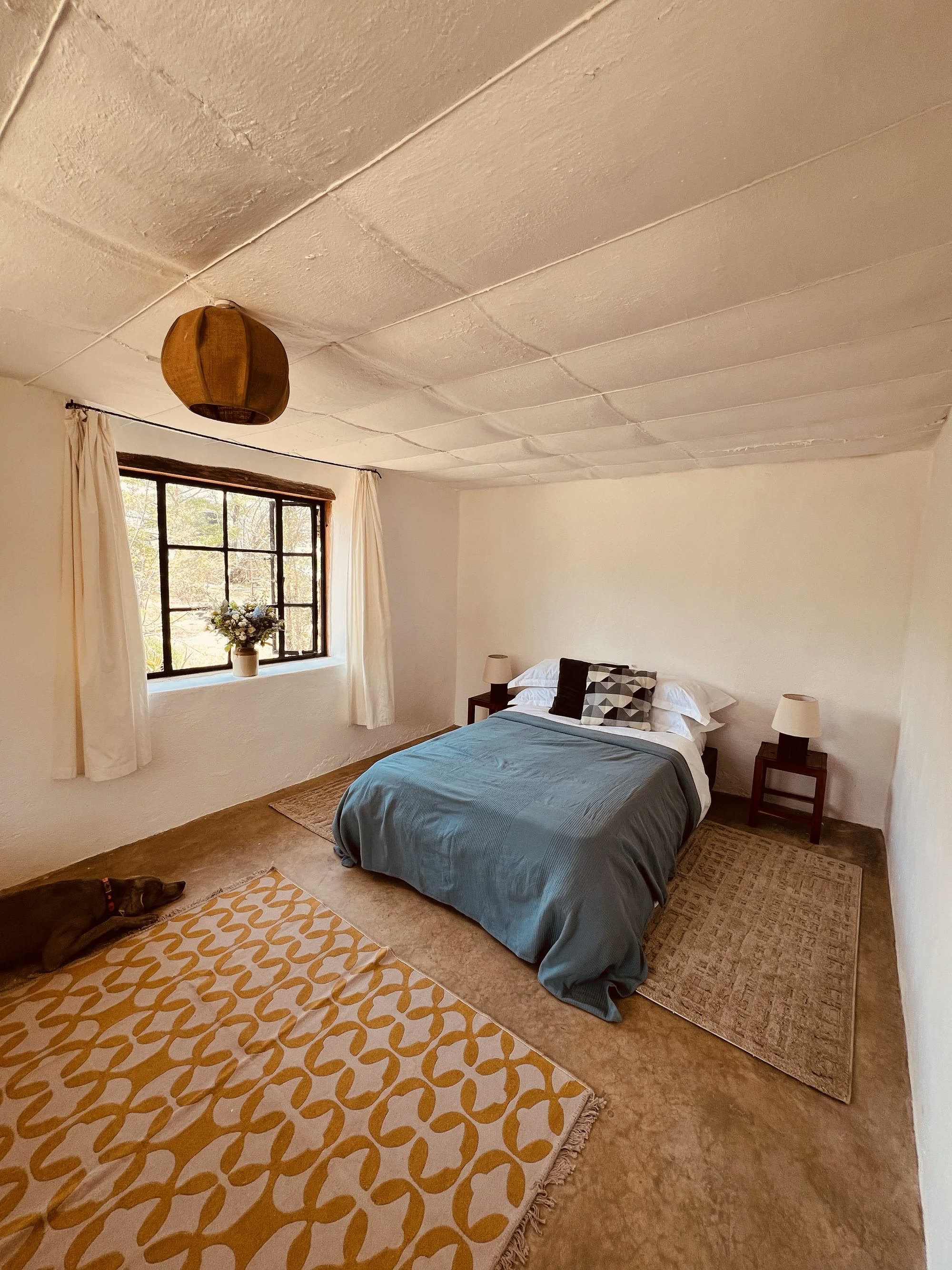 The twin room in the cottage at Laikipia Nest, with two single beds beside a curtained window.