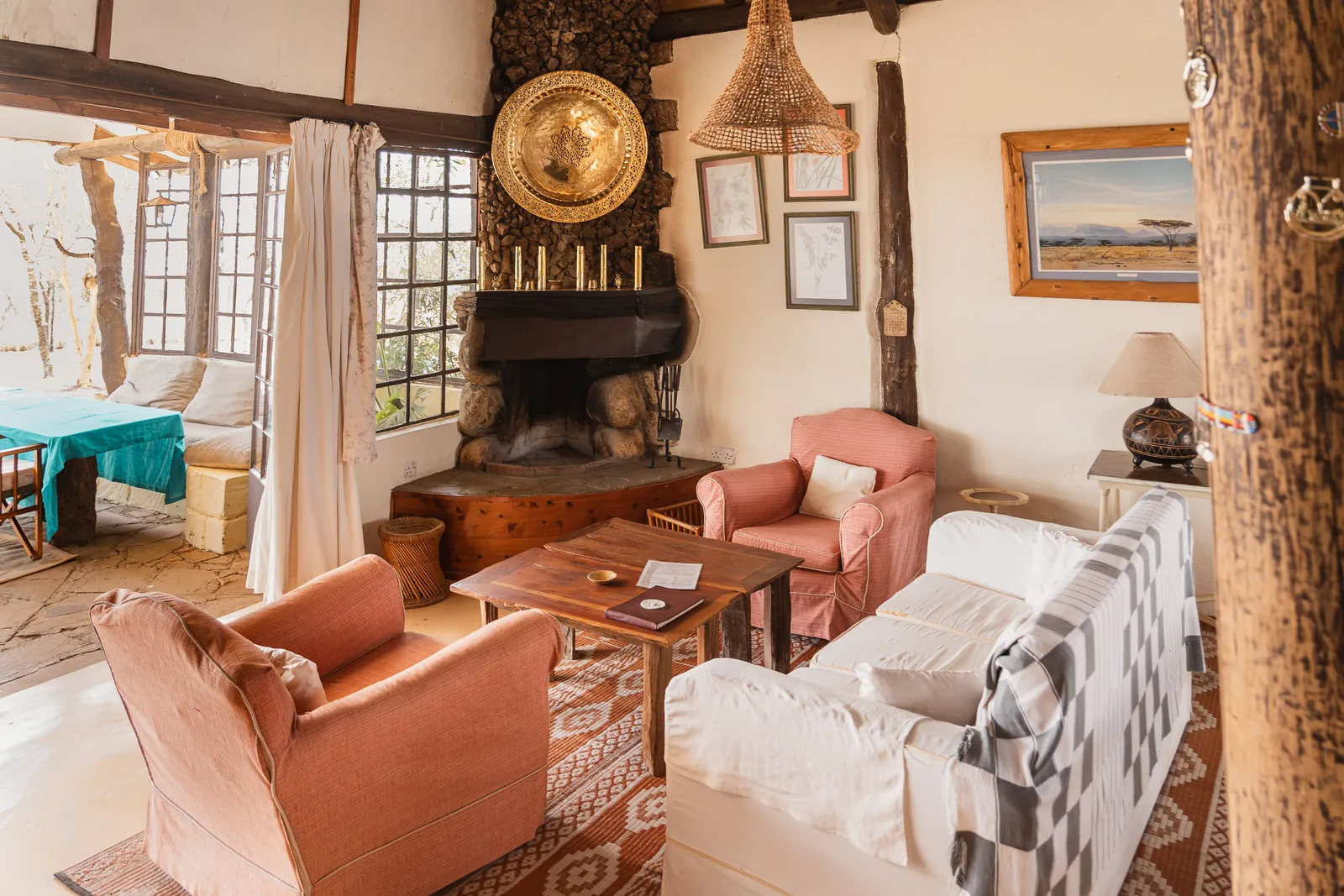 The sitting room at Champagne Ridge Nest, pink armchairs and a white sofa around a stone corner fireplace