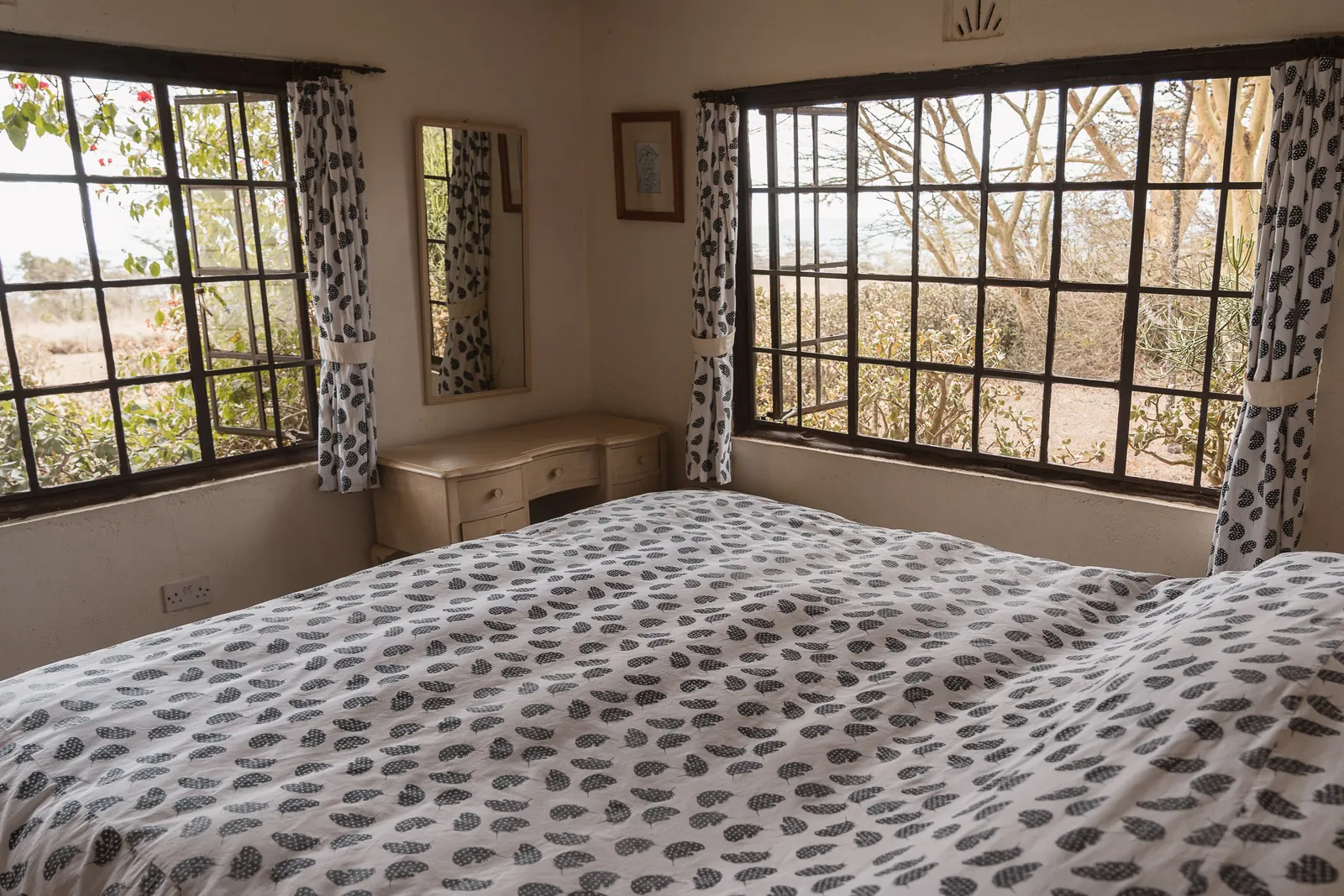 A double bedroom at Champagne Ridge Nest with patterned linen and corner windows onto the acacias