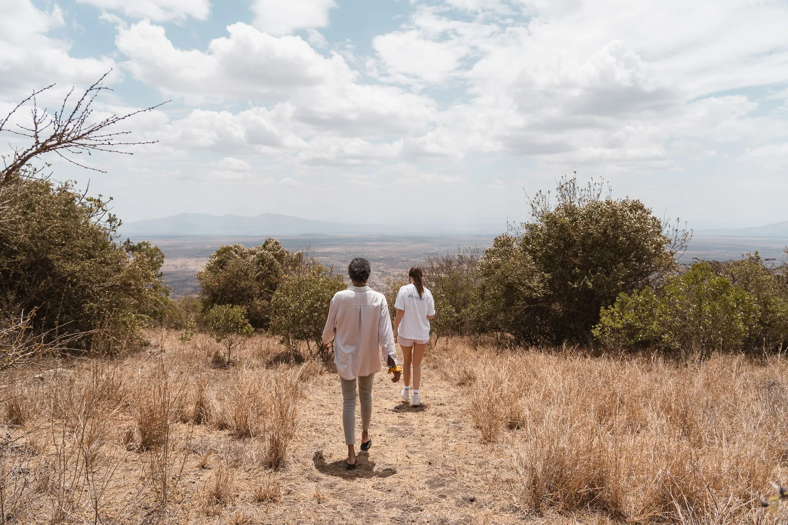 Two guests walking a path through dry grass towards the Rift Valley view at Champagne Ridge Nest